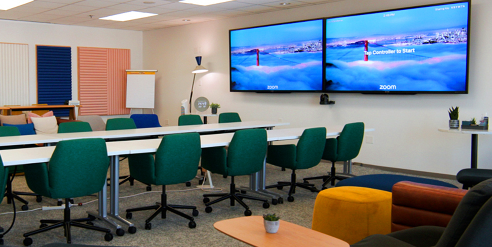 Image of a workspace showing screens and meeting table and chairs