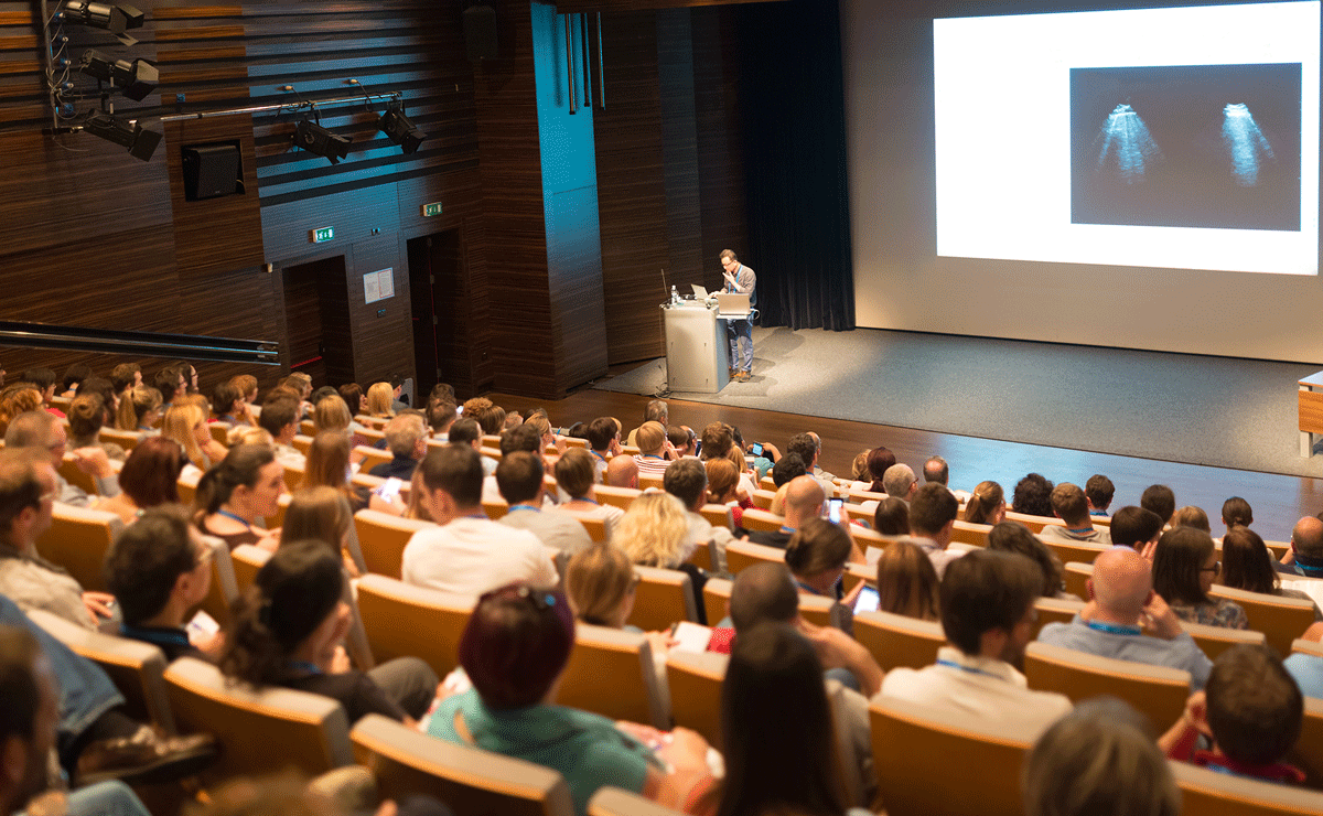 Large lecture hall filled with students, featuring Q-SYS peripherals